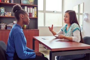 speech therapist working with playing cards with black teenage secondary school student